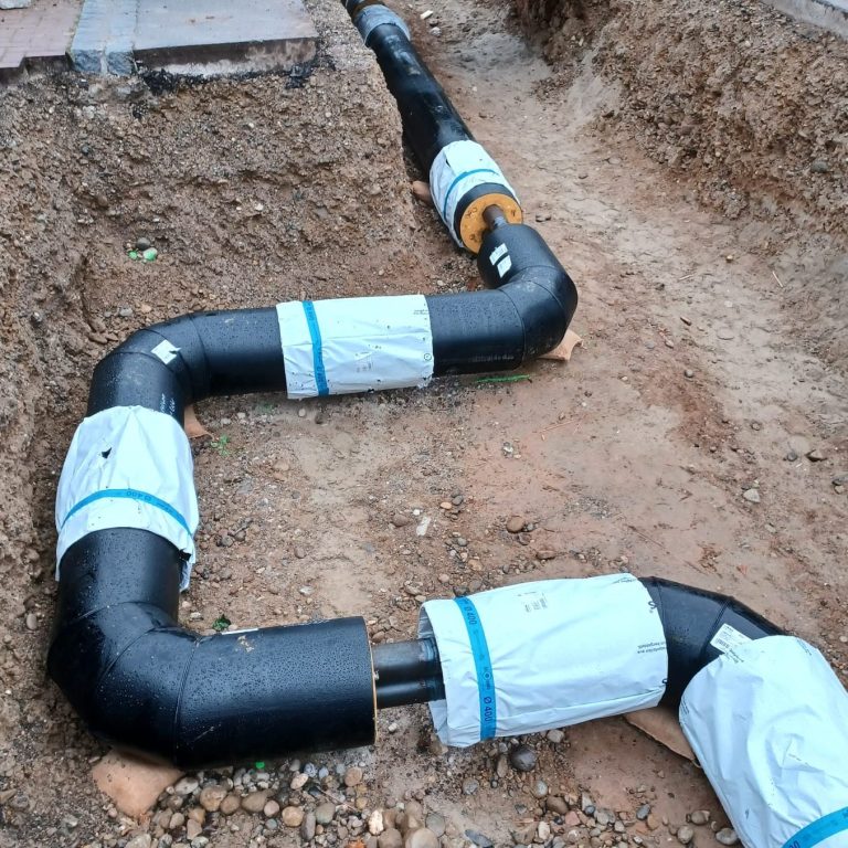 Sich im Bau befindlicher U-Dehner als Doppelrohrleitung, Gewerk Nahwärme in einer Baugrube.