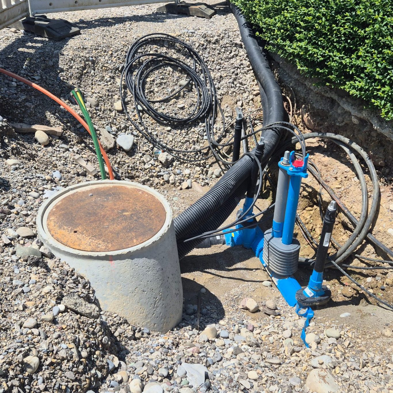 Blaue Formstücke Gewerk Wasser und gelbe Gasleitung in einer Baustelle mit freigelegtem Erdreich.